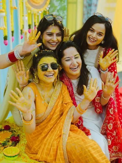The bride and her friends, all smiles and waving with turmeric-stained hands.