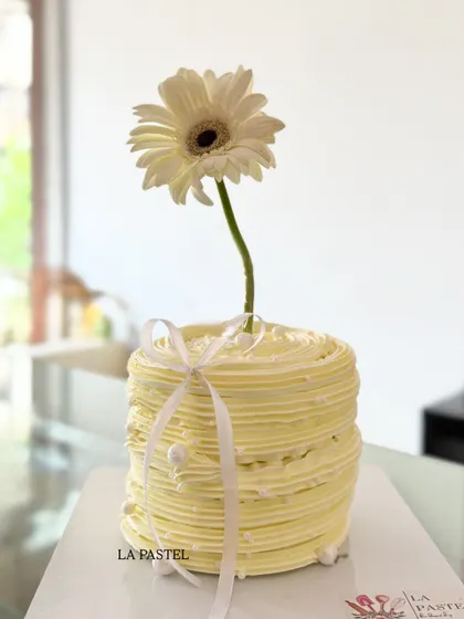 A minimalist yellow cake with a ribbed texture, decorated with a single white gerbera daisy. It's simple, fresh, and so pretty.