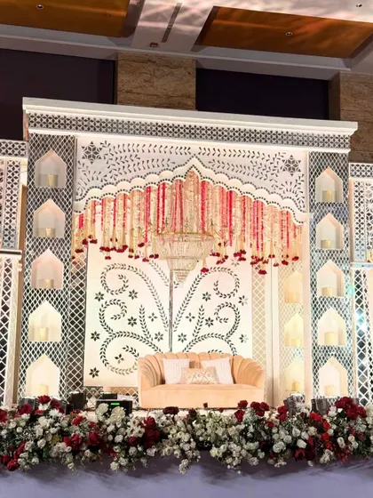 Elegance etched in ivory and gold. This reception stage, with its intricate jali work and candle-lit niches, was designed to be a perfect blend of royalty and romance.