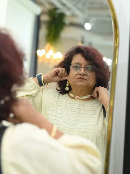 A moment of reflection. A client admires her reflection while trying on a pearl choker and matching earrings, ensuring the set is the perfect fit for her.