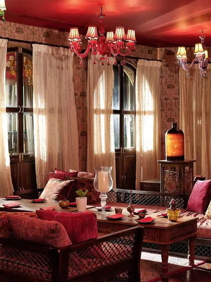 Sunlight streams through sheer curtains into one of our luxurious seating areas. The red chandeliers and plush, traditional seating create a warm and regal atmosphere for daytime indulgence.