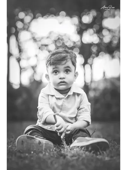 A soulful black and white portrait of Ivaan sitting in the grass. The soft focus and his direct gaze make this a simple but deeply engaging photograph.
