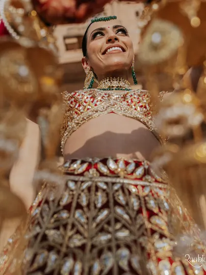 A joyful, upward-looking shot of the bride, Amala, framed by her golden kaleeras, capturing a moment of pure happiness.