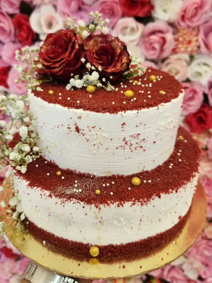 A two-tiered red velvet cake, decorated with fresh roses and baby's breath. The rich red crumbs give it a classic and delicious look.