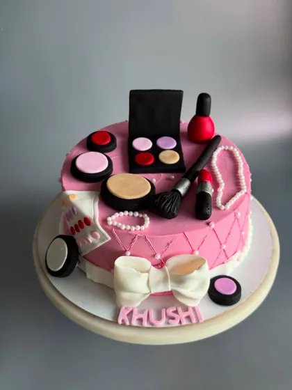 A full view of the adorable makeup-themed cake for Khushi. The quilted pink design and big white bow add a touch of glamour.