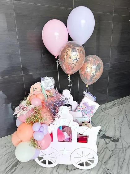 The pink chariot hamper, complete with confetti balloons, ready to celebrate a baby girl's arrival. This grand gift is designed to make a lasting impression.