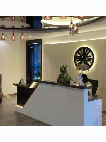 This image captures the refined material palette of the reception, with a high-gloss desk, a classic wingback chair, and elegant pendant lights, all contributing to a sophisticated corporate environment.
