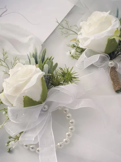 It's all in the details. This set features a classic white rose wrist corsage with a pearl bracelet for the mothers of the bride and groom, perfectly paired with a matching boutonniere for the fathers. These small touches make your closest family feel special and included.