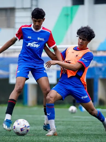 Two U19 players battle for possession in a high-intensity drill. Training at this level is designed to replicate the physical demands of professional football.