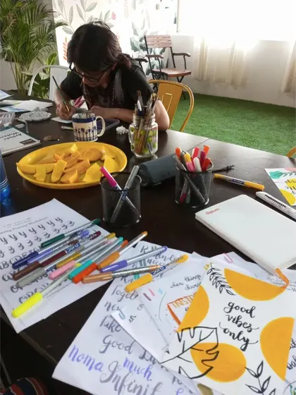 A participant immersed in a calligraphy session, with practice sheets and colorful pens spread across the table. My workshops are designed to provide a therapeutic escape through focused, creative tasks.