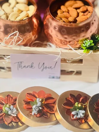 A deconstructed view of a corporate gift, showing the copper jars filled with cashews and almonds. The floral-topped lids are a beautiful detail.