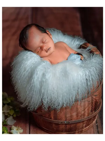 Another angle of the newborn in the bucket, showcasing the baby's peaceful sleep.