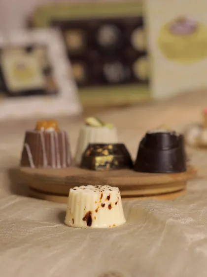 An assortment of our soft-centered chocolates, showcasing the variety of shapes and toppings. Flavors include tiramisu, caramel, and pista kunafa, each offering a unique taste experience.
