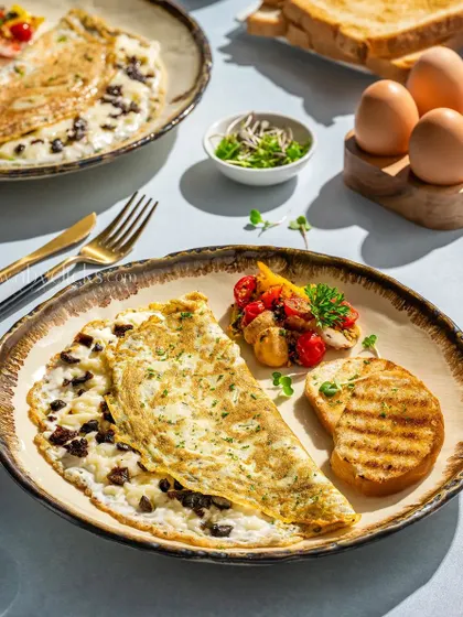 A fluffy, folded omelette with a mushroom filling, served with grilled toast and sauteed vegetables.