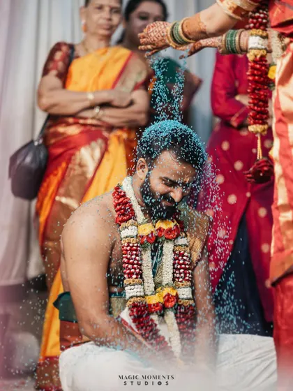 A powerful shot of the groom, Akash, during the Akshata ritual, where he is showered with blue-colored rice, creating a visually stunning image.