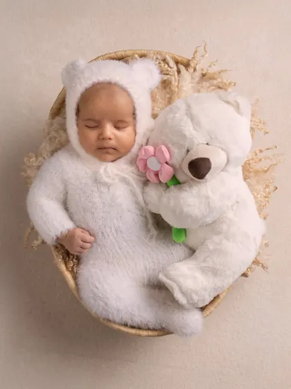 Sweet dreams. A close-up of a baby in a fuzzy bear costume, snuggled up with her teddy. A simple and adorable concept.