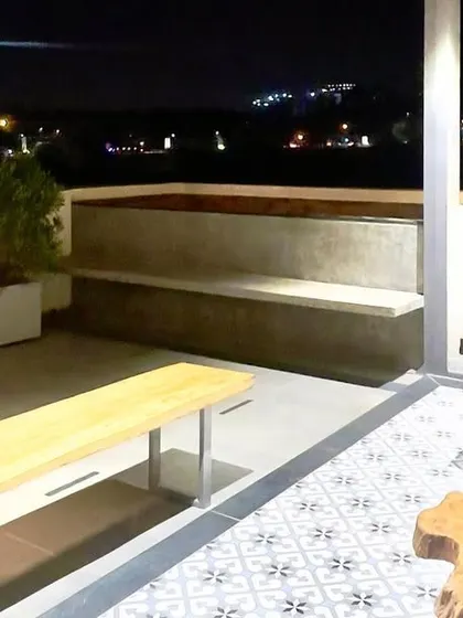 The terrace at night, transformed into a cozy spot with views of the city lights. The design includes built-in seating and planters to maximize the use of space.