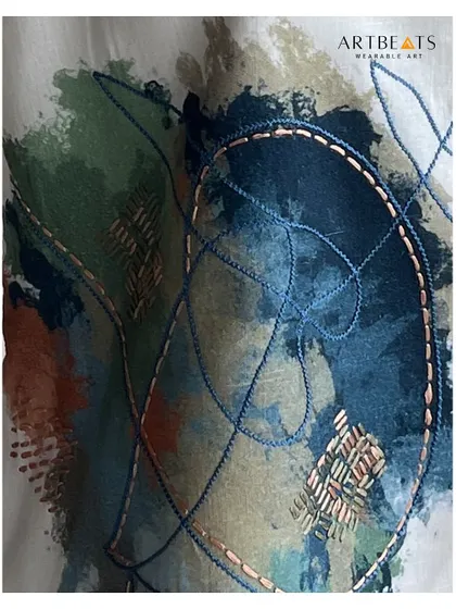 A close-up of the 'Reverie' piece from the Rooted collection. You can see the interplay of abstract painting with delicate hand embroidery and thread work. This detail shows how each garment is a unique piece of textile art.