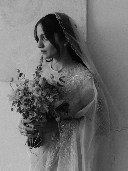 A beautiful black and white portrait of a Christian bride holding her bouquet. Her gentle, thoughtful expression and the soft texture of her veil create a delicate and timeless image.