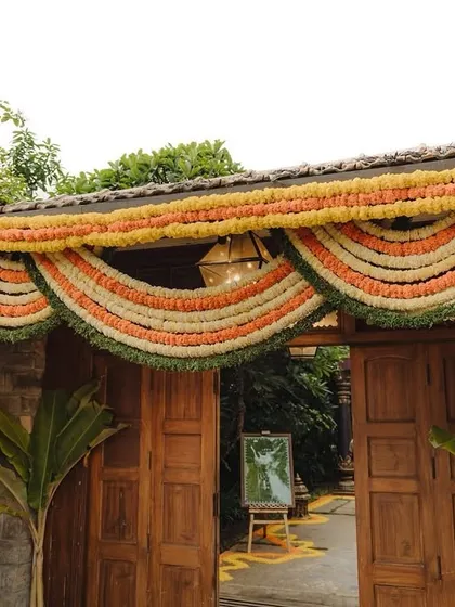 An entrance to a traditional home decorated with beautiful marigold torans, welcoming guests to the celebration.