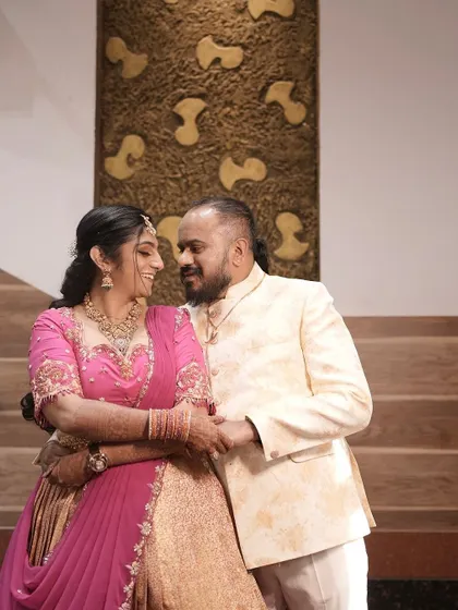 A happy couple at their engagement, the bride-to-be glowing in a custom pink and gold half saree.