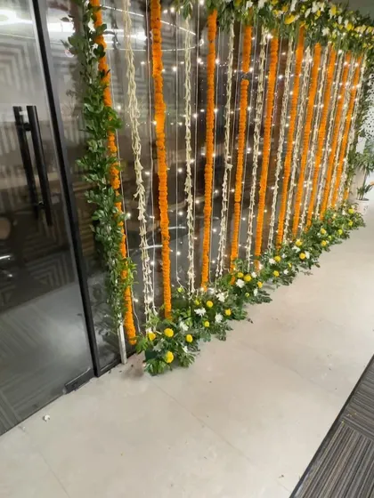 A beautiful wall decoration for an office Diwali party, using strings of marigold and tuberose flowers interwoven with fairy lights.