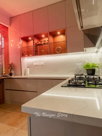 A view from the corner of the L-shaped kitchen, showing the white quartz countertop and the stylish amber chandelier over the dining area. The design ensures a smooth workflow and a beautiful aesthetic.