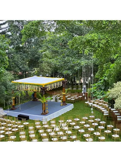 An aerial perspective of the entire wedding setup. The grand mandap, surrounded by guest seating, is nestled in a lush green landscape, creating a picturesque setting for a memorable celebration.