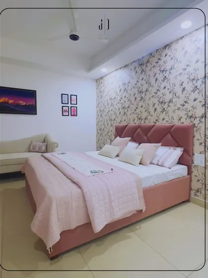 A lovely bedroom design featuring a soft pink upholstered bed and floral wallpaper. This room is a perfect example of creating a feminine and romantic space that is both cozy and chic.