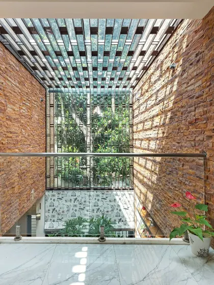 Another view of the skylight and stone-clad walls of the Twin Courtyard. The design prioritizes both security, with the MS grill, and aesthetics, with the play of light on natural textures.