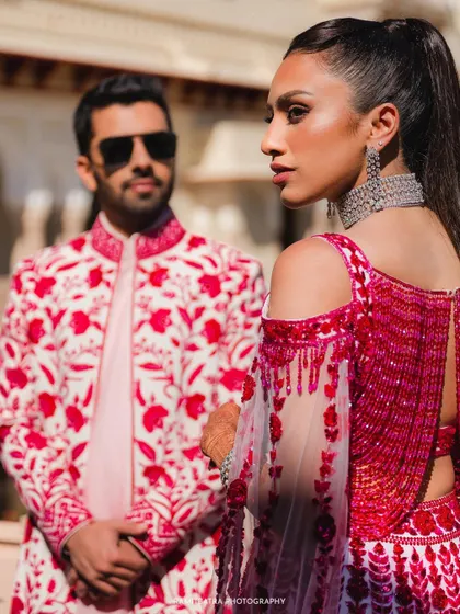 A stylish, editorial-style portrait of the couple, with the groom slightly out of focus in the background.