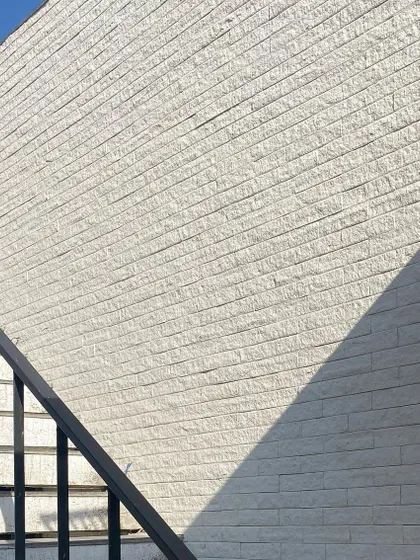 A detail of the textured white brickwork and shadows at Pavilion House during construction.