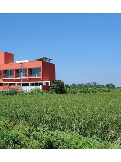 The residential or guest house block of the Sai Temple complex, set against the vast agricultural landscape of Trichy.