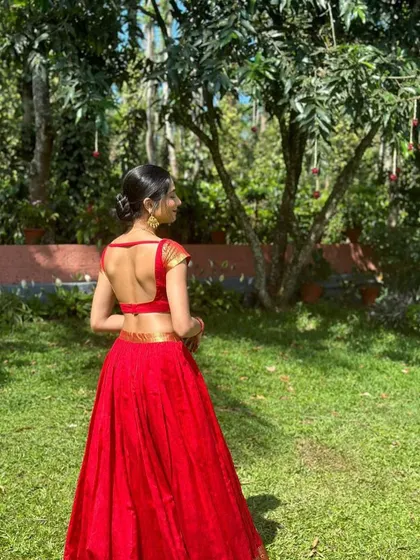 A modern take on a traditional lehenga. This monochromatic red ensemble features a simple crop top with a deep back and elegant Banarasi border detailing on the cap sleeves, paired with a flowing red skirt.
