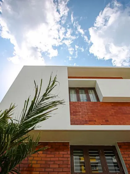A detail shot of the MV Residence facade, looking up at the interplay between the brick wall, white cantilevered elements, and the sky.