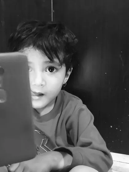The child's expression of curiosity while looking at the phone screen. Black and white photography helps to focus on the emotion and the story in the child's eyes.