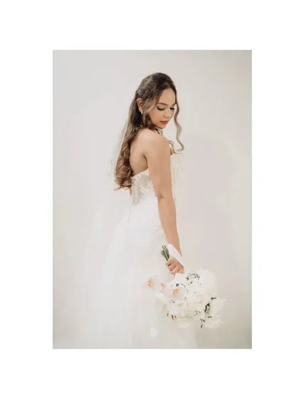 A simple, elegant portrait of the bride holding her bouquet. The clean background and soft light create a timeless and beautiful image.