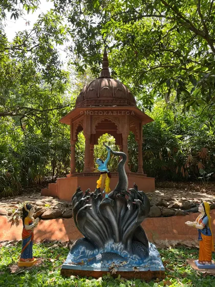 A depiction of Krishna subduing the Kaliya serpent, set in a small pavilion amidst the greenery of Govardhan Ecovillage.
