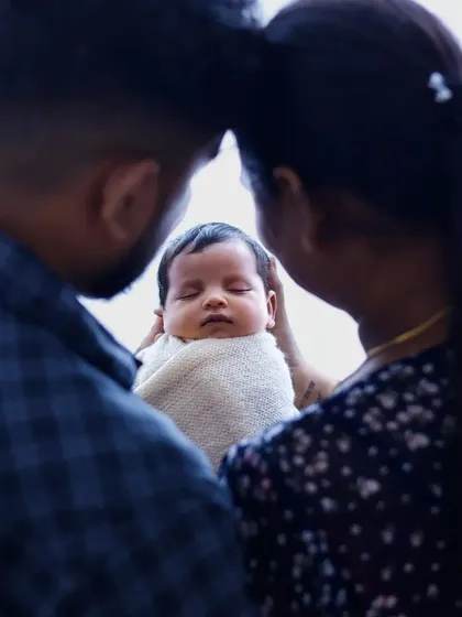An over-the-shoulder view of parents admiring their baby, creating a sense of intimacy and love.
