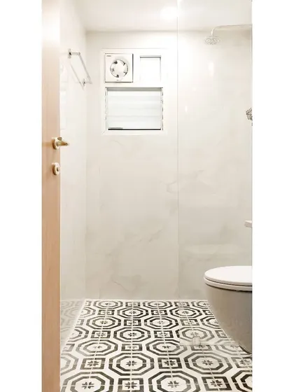 After: The transformed guest bathroom. The star of the show is the gorgeous black and white patterned cement tile on the floor, which provides a stunning foundation. The marble-look wall tiles and frameless glass shower keep the space feeling bright and clean.