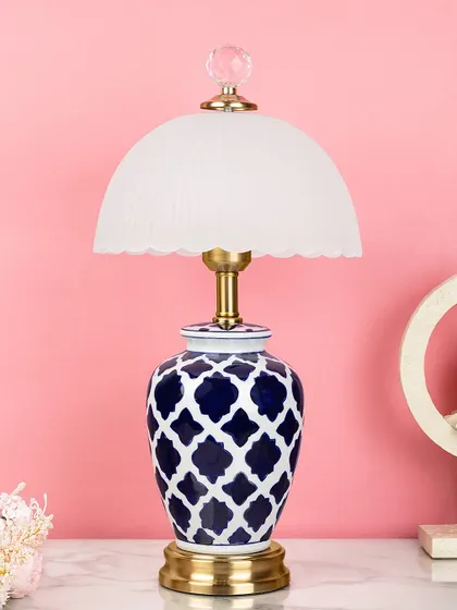 This ceramic table lamp features a modern Moroccan tile pattern in deep blue and white, topped with a frosted glass dome shade. It's a unique piece that provides soft, diffused light.
