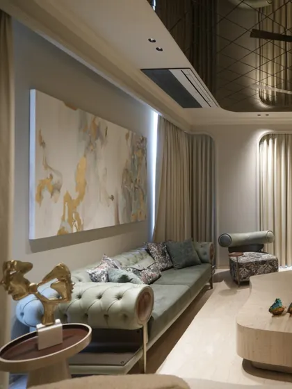 The olive green sofa with its classic tufting is complemented by a large abstract painting that introduces soft gold and blue tones. This composition shows how we use art to tie a room's color story together.