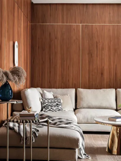 A close-up of a cozy corner in a living room. The warm wood paneling creates a cocoon-like feel, perfect for a comfortable L-shaped sofa. This is a space designed for relaxing and unwinding.