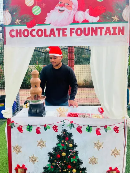 Our staff member, dressed for the occasion in a Santa hat, manages the chocolate fountain at a Christmas party, ensuring everything runs smoothly.