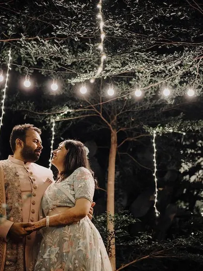 A magical evening portrait under a canopy of string lights. The soft glow creates a romantic and dreamy ambiance, perfect for capturing the couple's love story.