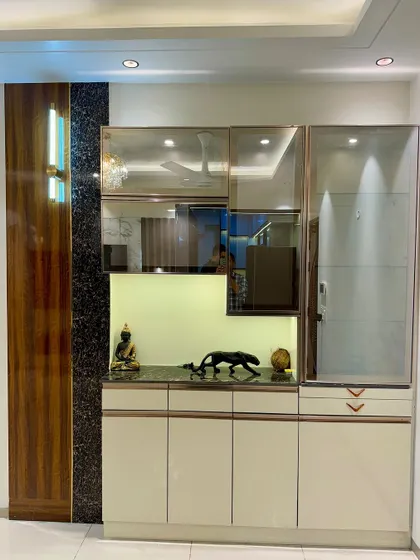 A stylish crockery unit with a mix of wood-finish and high-gloss laminates. The asymmetrical design of the glass cabinets adds a modern touch.