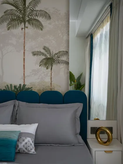 A close-up of the tropical guest bedroom's scalloped teal headboard set against the palm tree wallpaper, creating a five-star escape feel.