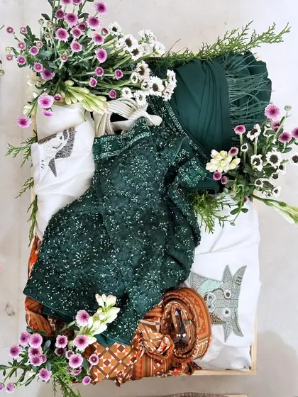 An overhead view of the dark green outfit tray, showcasing the rich color and texture, enhanced by the fresh floral arrangement.
