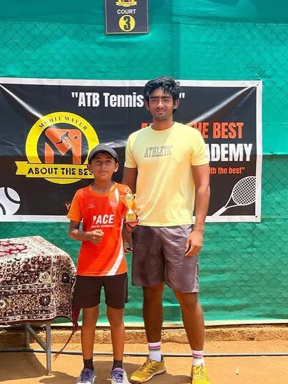 A young champion receives his trophy from a senior player at our academy, inspiring the next generation.