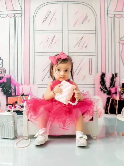 Welcome to the Barbie dream house. This little girl is ready for her first birthday party, holding a stylish purse in a chic, pink and black illustrated setting.